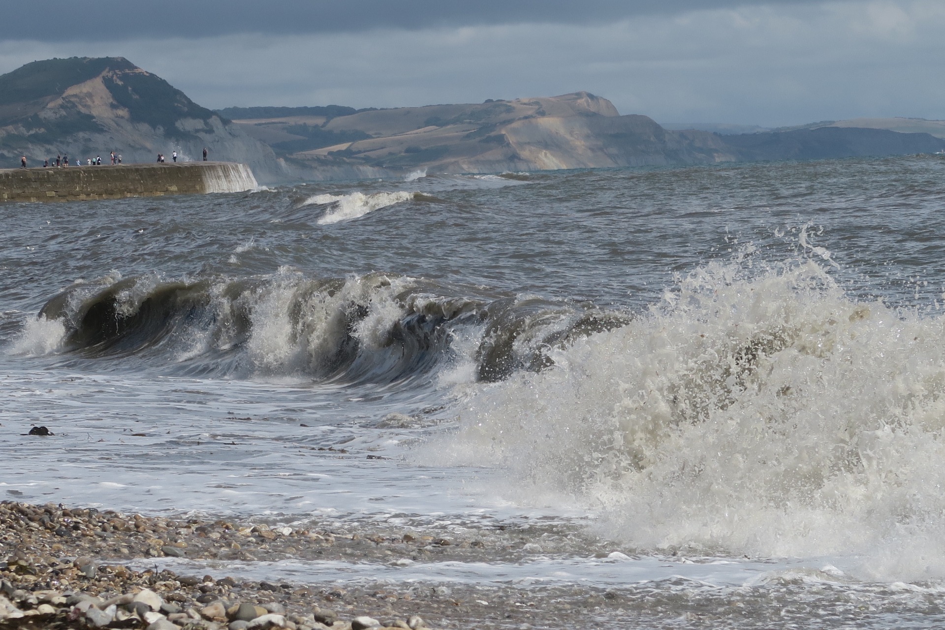 Lyme Regis, looking east, with people walking on The Cobb. (K.B.)